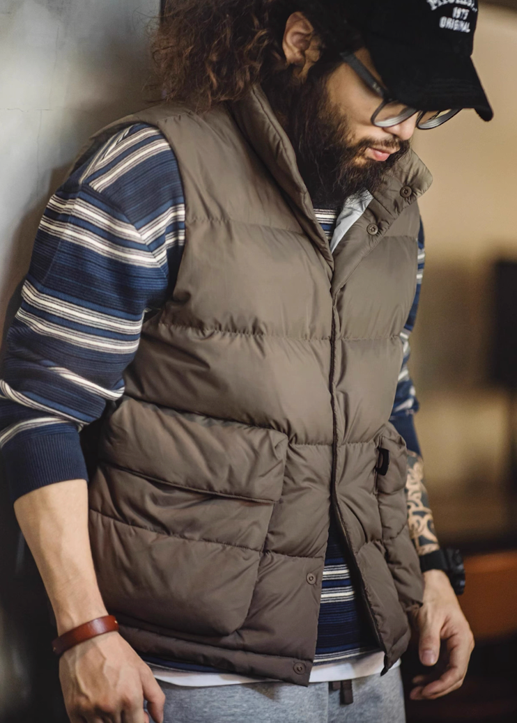 Side angle of model in Mud Brown Heritage Down Vest in indoor setting