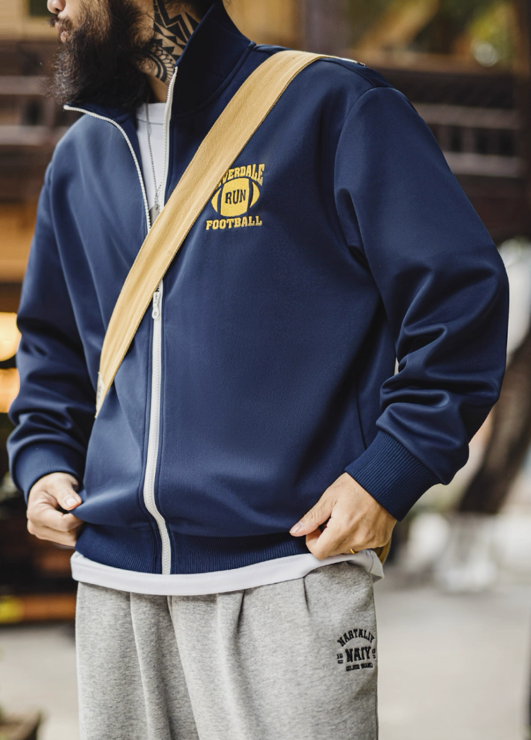 Model outdoors in navy Riverdale Run track jacket with shoulder bag