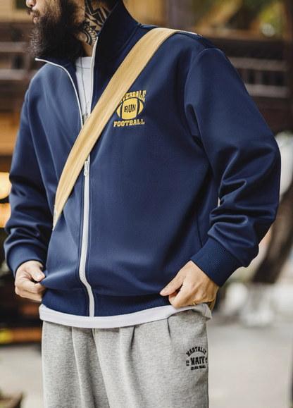 Model outdoors in navy Riverdale Run track jacket with shoulder bag