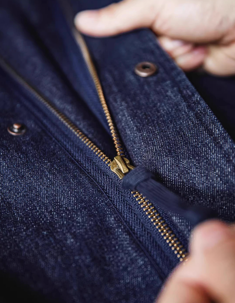 Close-up of brass zipper on premium denim fishtail parka
