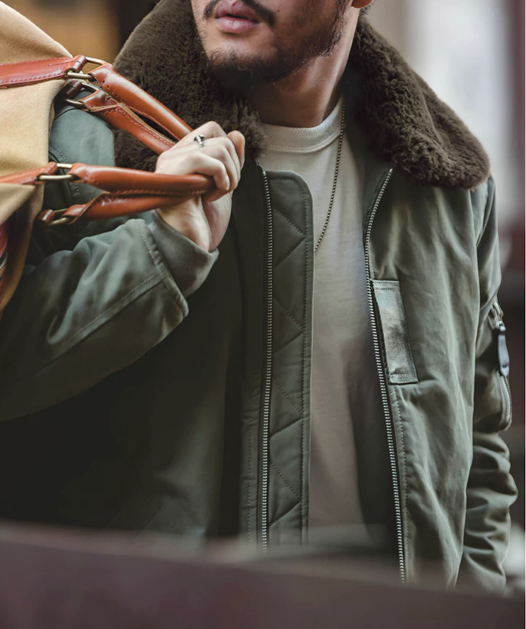 Man carrying bag wearing green B-15 flight jacket with faux fur collar