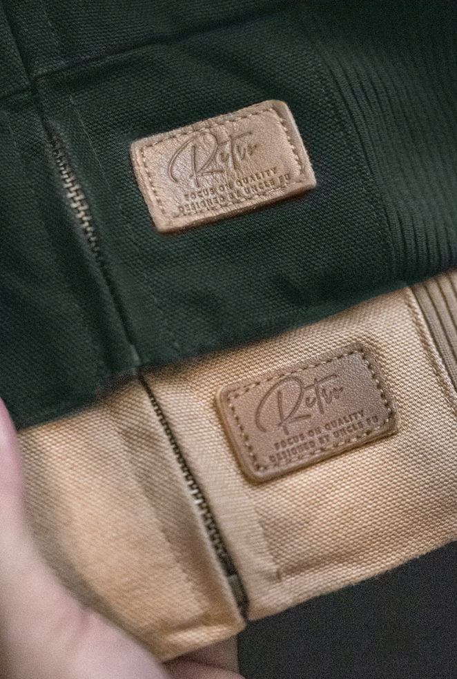 Close-up of brown leather logo patch on hem of Santafe retro workwear jacket.