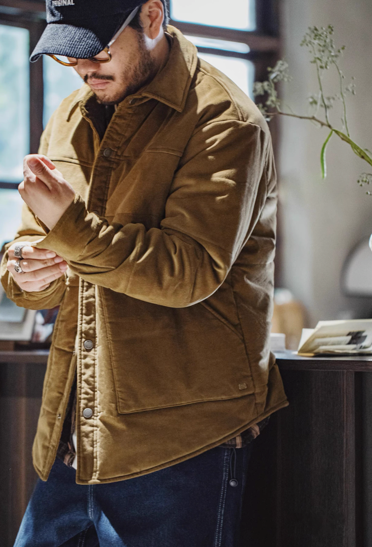 Man adjusting sleeve cuff of brown corduroy padded jacket indoors
