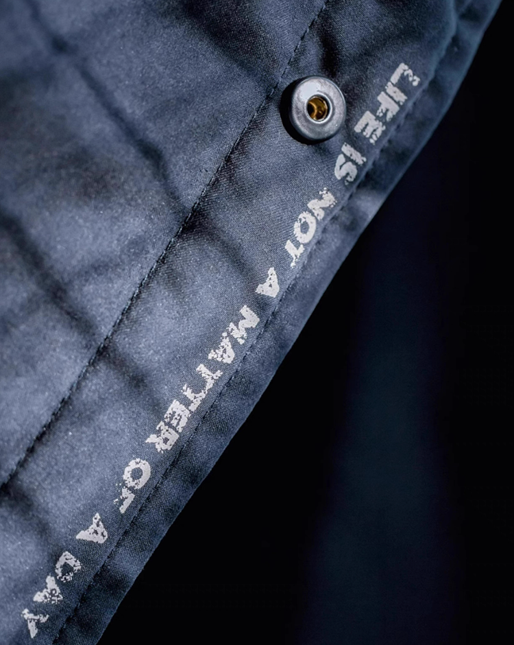 Close-up fabric detail showing “Life Is Not A Matter Of A Day” print and button finish