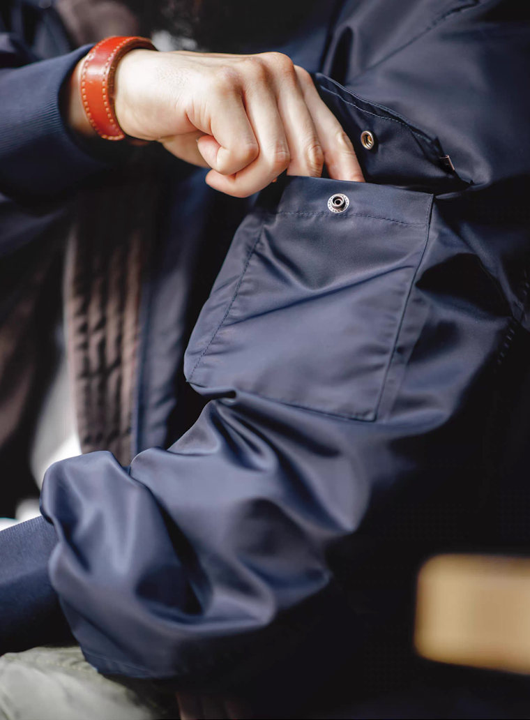 Close-up of man using snap-button utility pocket on the sleeve of the G-8 Navy Flight Jacket.