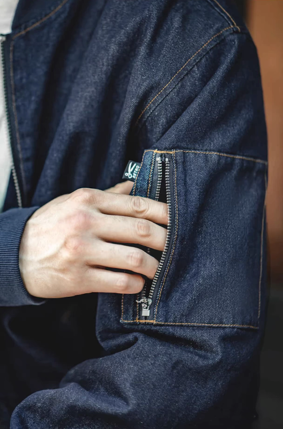 Detail view of functional sleeve zipper pocket on denim MA-1 jacket