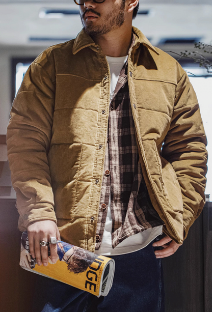 Man styling brown corduroy jacket with plaid shirt and jeans