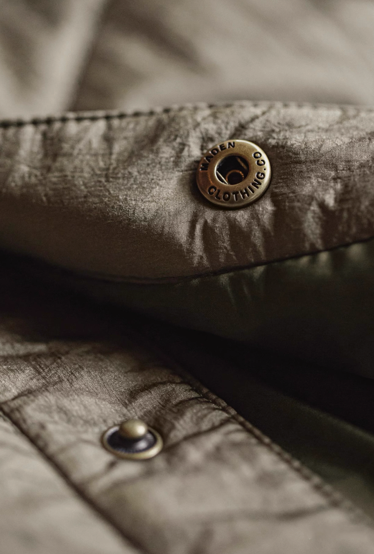 Metal snap button engraved with brand lettering on nylon fabric