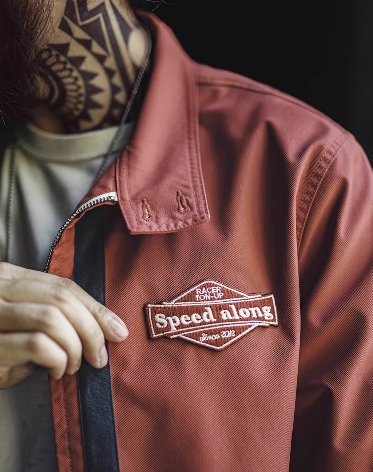 Detail view of embroidered Speed Along patch on chest of 60s racing jacket