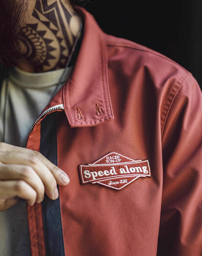 Detail view of embroidered Speed Along patch on chest of 60s racing jacket