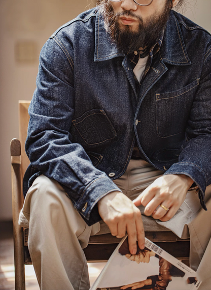 Model seated wearing denim chore coat with heritage-style design