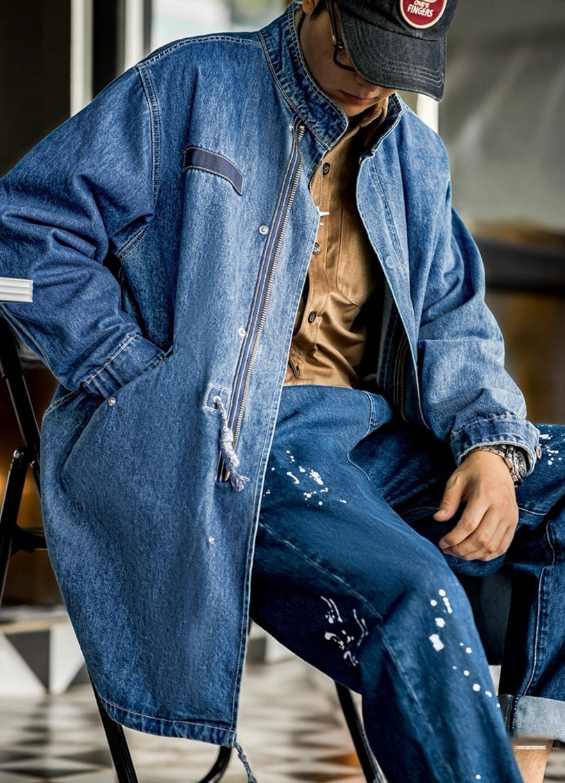 Close-up of model sitting wearing denim M-65 parka with drawstring detail