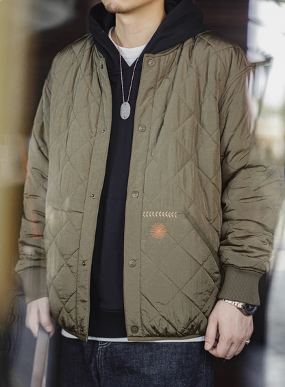 Model wearing olive quilted bomber jacket over layered streetwear look