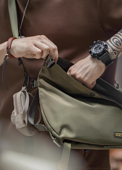 Close-up of man opening olive Yama Style crossbody messenger bag