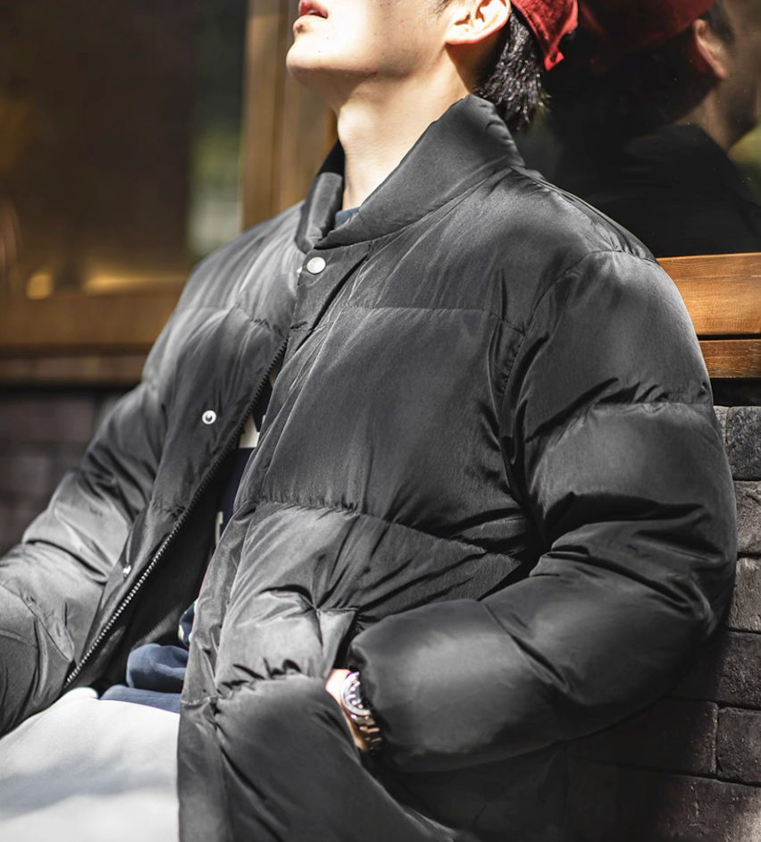 Side view of model in black Dual-Tone Down Jacket highlighting fabric shine