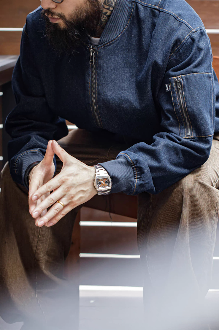 Model sitting with denim MA-1 bomber jacket and brown corduroy pants
