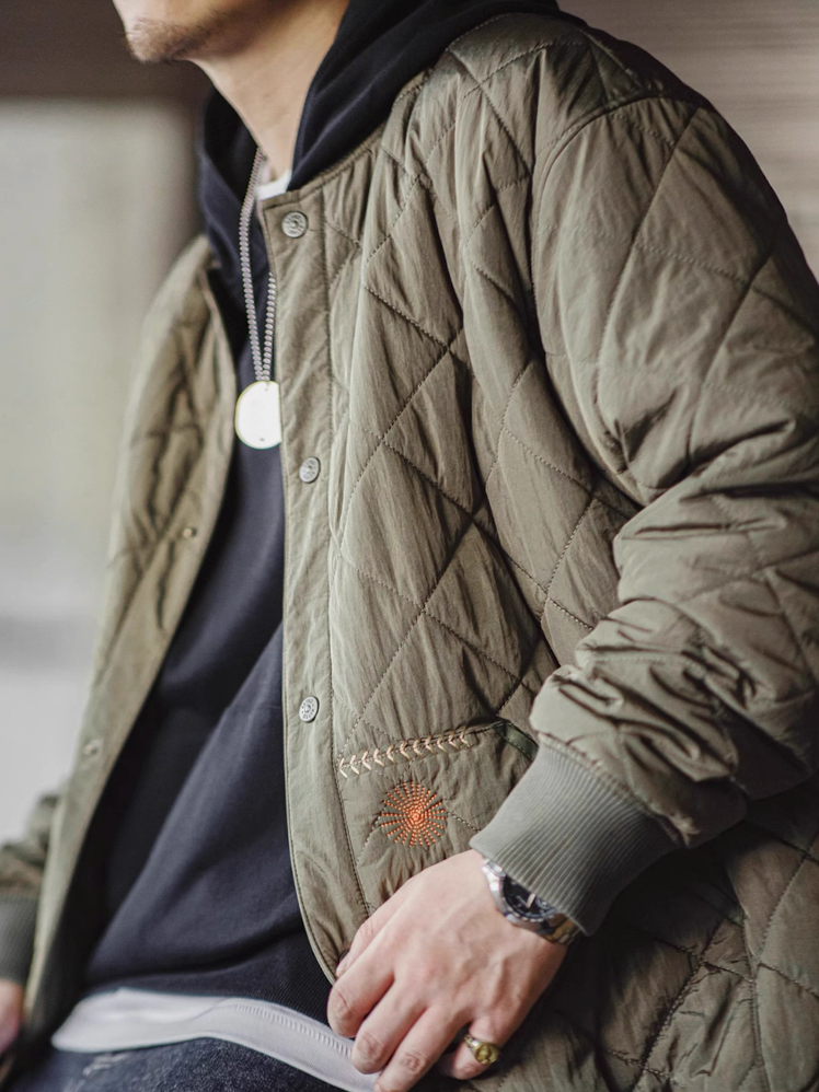 Side angle of man styling lightweight diamond quilted bomber jacket