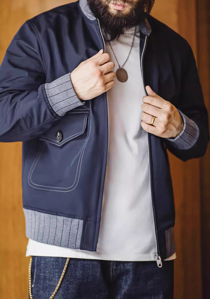Man zipping up navy A1 flight jacket in casual indoor setting