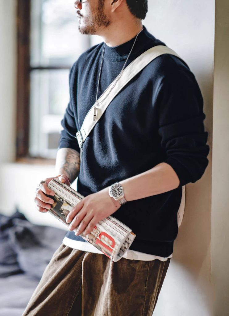 Man wearing navy blue sweater with brown corduroy pants