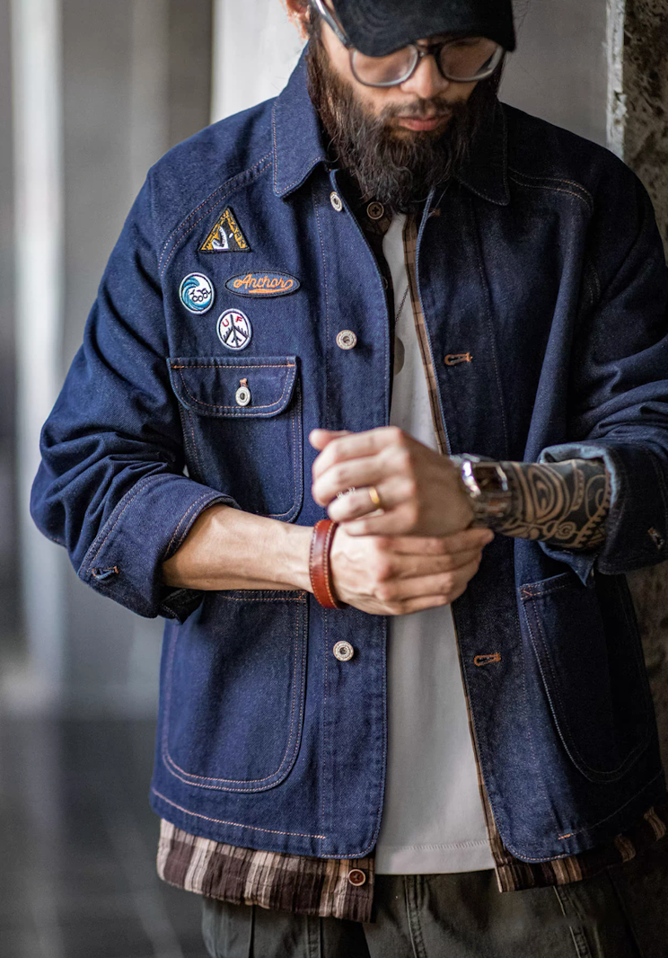 Man adjusting cuff of denim chore jacket showing patch details
