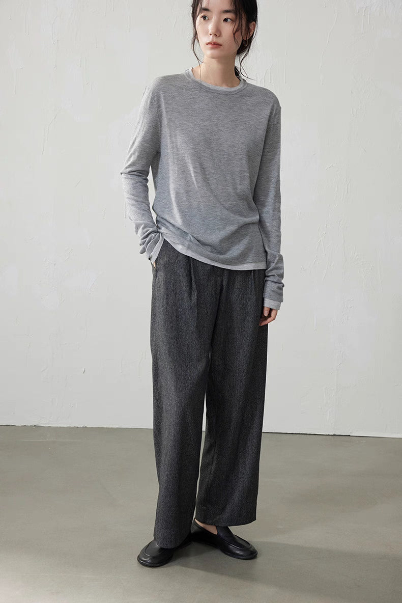Model wearing light gray double-layer knit top with gray wool pants in minimalist room