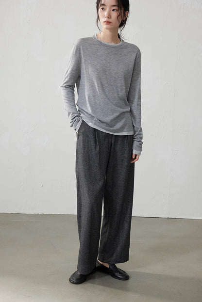 Model wearing light gray double-layer knit top with gray wool pants in minimalist room