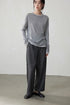 Model wearing light gray double-layer knit top with gray wool pants in minimalist room
