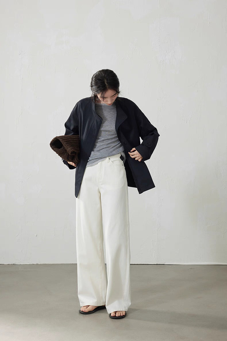 Model in light gray top paired with navy jacket and ivory wide-leg pants carrying brown tote