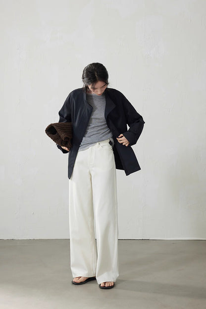 Model in light gray top paired with navy jacket and ivory wide-leg pants carrying brown tote