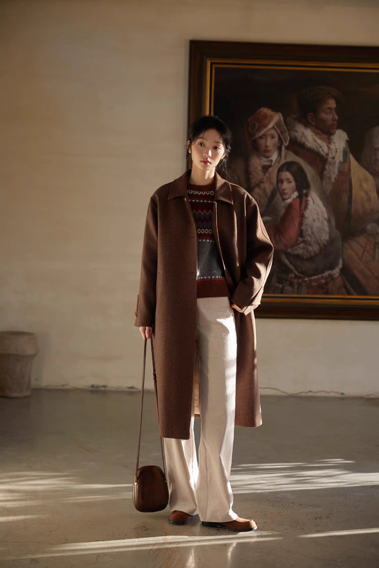 Model layering Fair Isle wool sweater under brown wool coat, full-body view