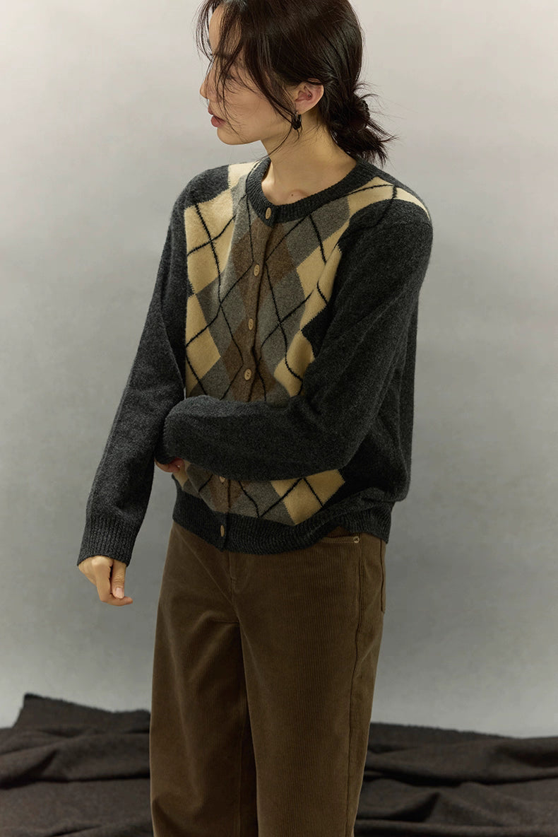 Model standing side profile wearing argyle cardigan with beige and brown diamond pattern