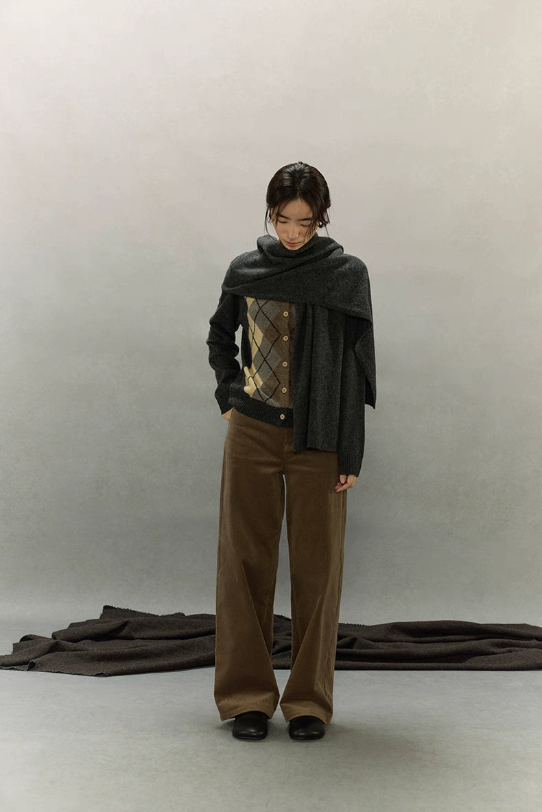 Model with scarf draped over cardigan in minimalist studio setting showcasing cozy texture