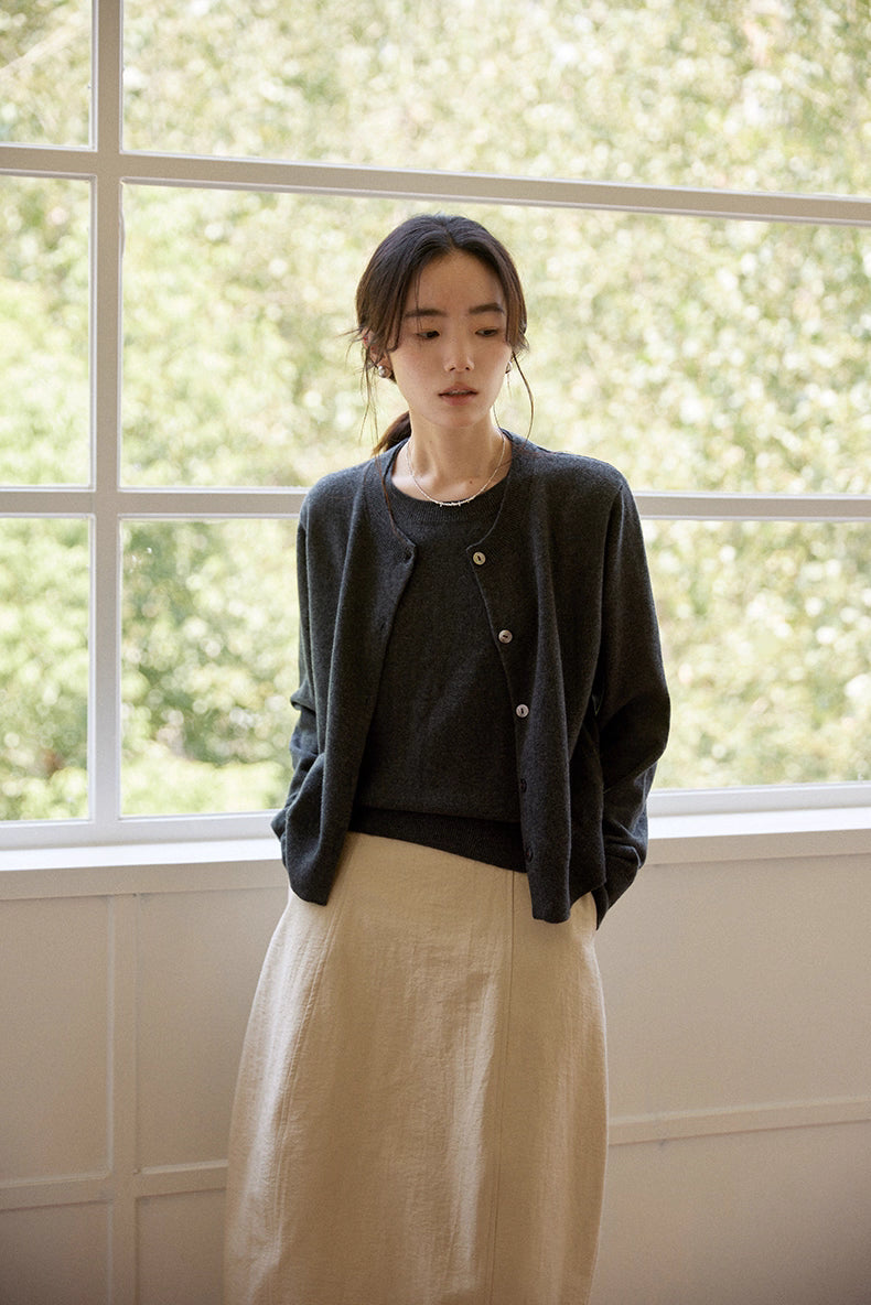 Relaxed front view of twin-layer wool cardigan paired with beige skirt