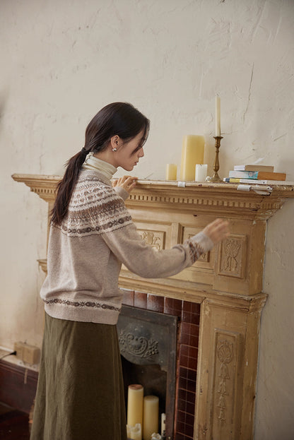 Side-back view of model adjusting candles on fireplace wearing beige Fair Isle cardigan
