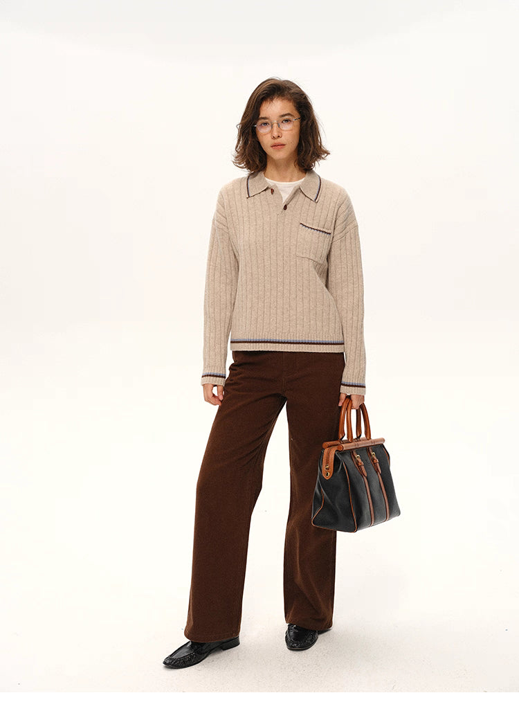 Full-body front view of woman wearing ribbed wool polo sweater with brown trousers.