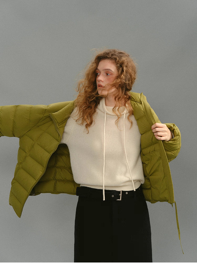 Model opening mustard green puffer to show lining and relaxed fit.