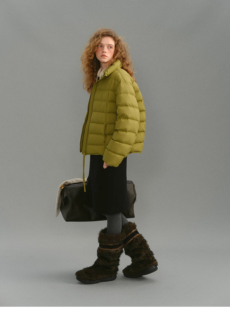 Side shot of model wearing mustard green down puffer with winter boots.