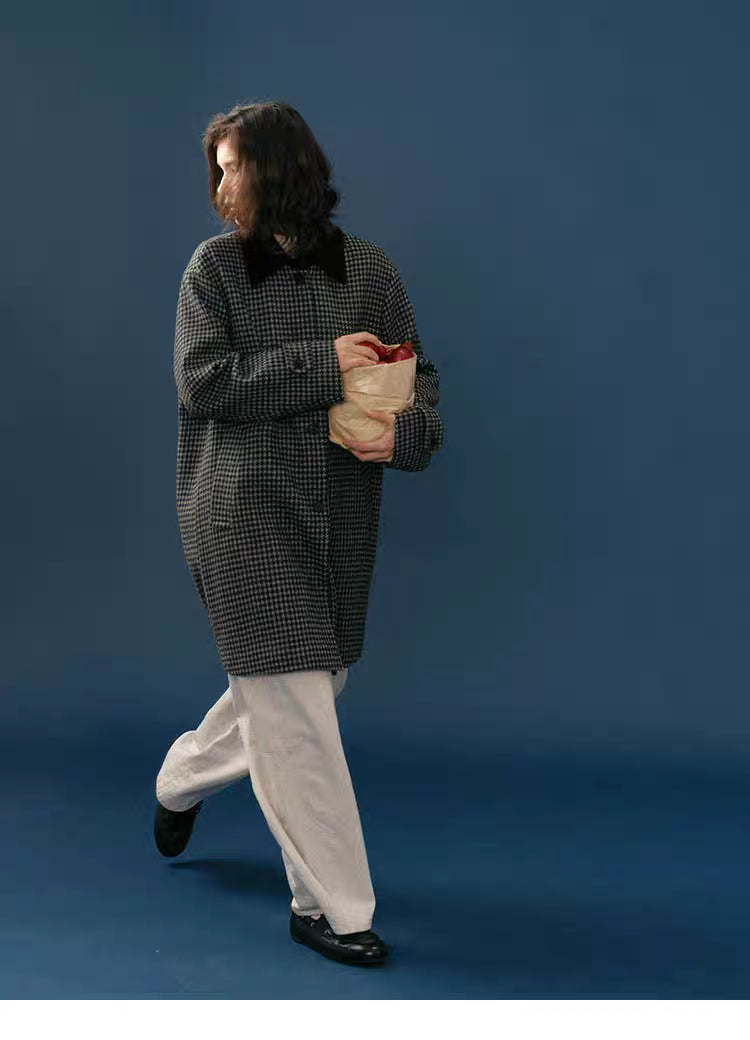Full-body walking shot of model wearing a mid-length midnight houndstooth wool coat.