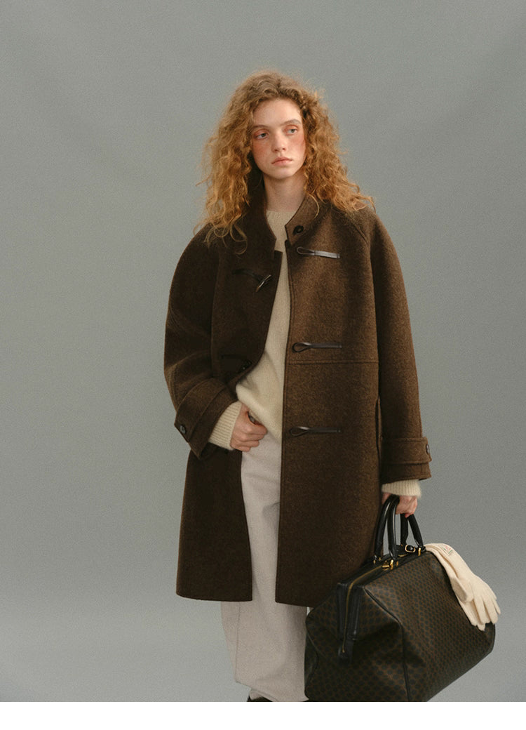 Brown alpaca-wool toggle coat front view on model with travel bag.