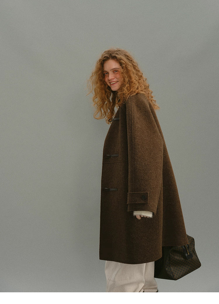 Model walking in brown toggle coat showing mid-length drape.