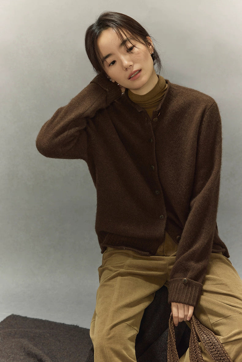 Model seated wearing dark coffee yak wool round-neck cardigan and camel trousers, relaxed winter look