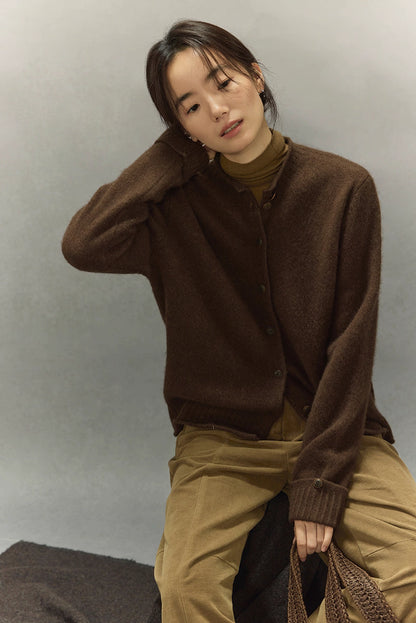 Model seated wearing dark coffee yak wool round-neck cardigan and camel trousers, relaxed winter look
