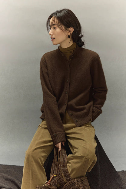 Side profile of woman seated in dark coffee yak wool cardigan layered over olive turtleneck