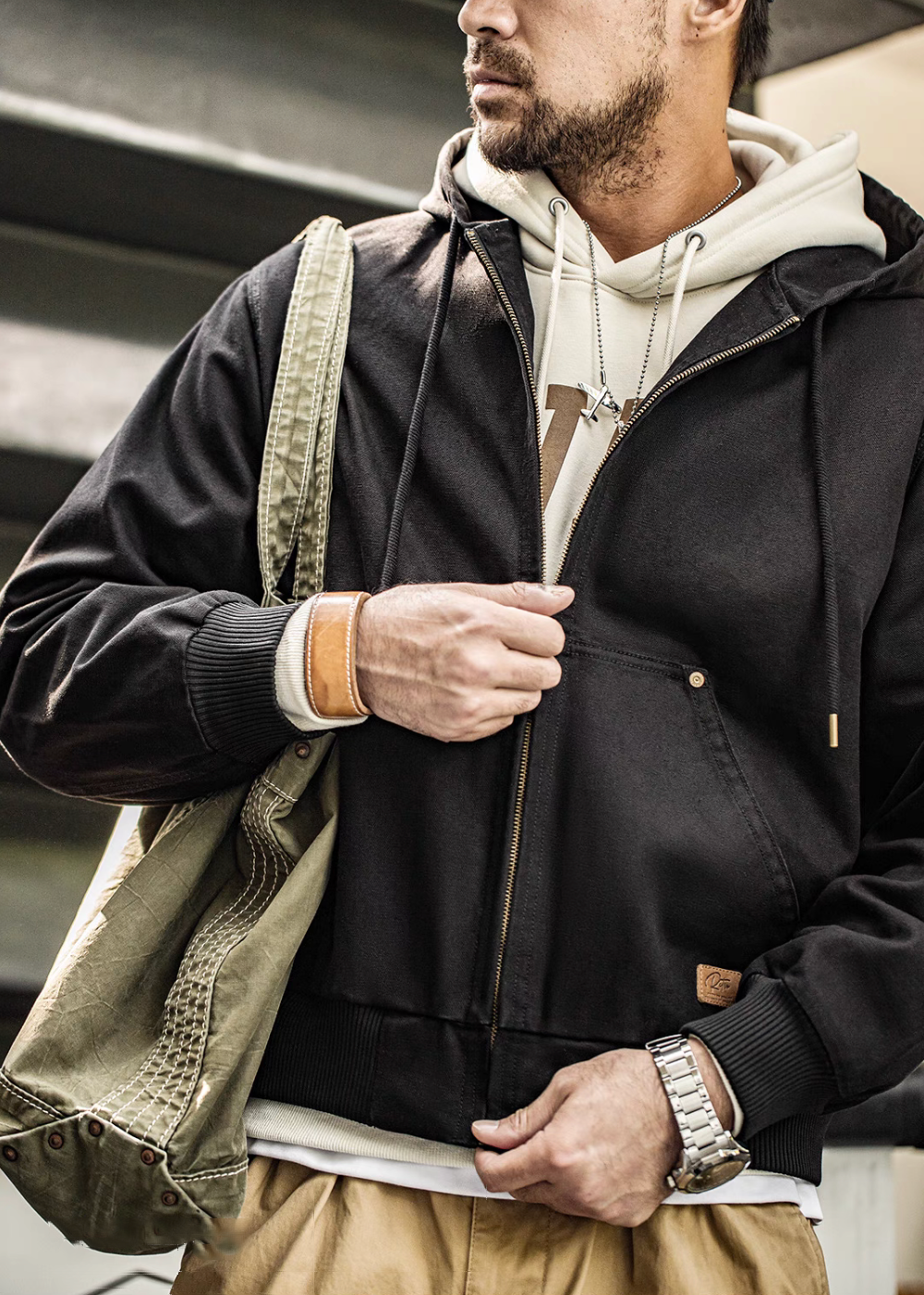 Close-up of Black Adventure Ready Hooded Jacket worn by model adjusting front zipper highlighting cotton texture and pocket detail