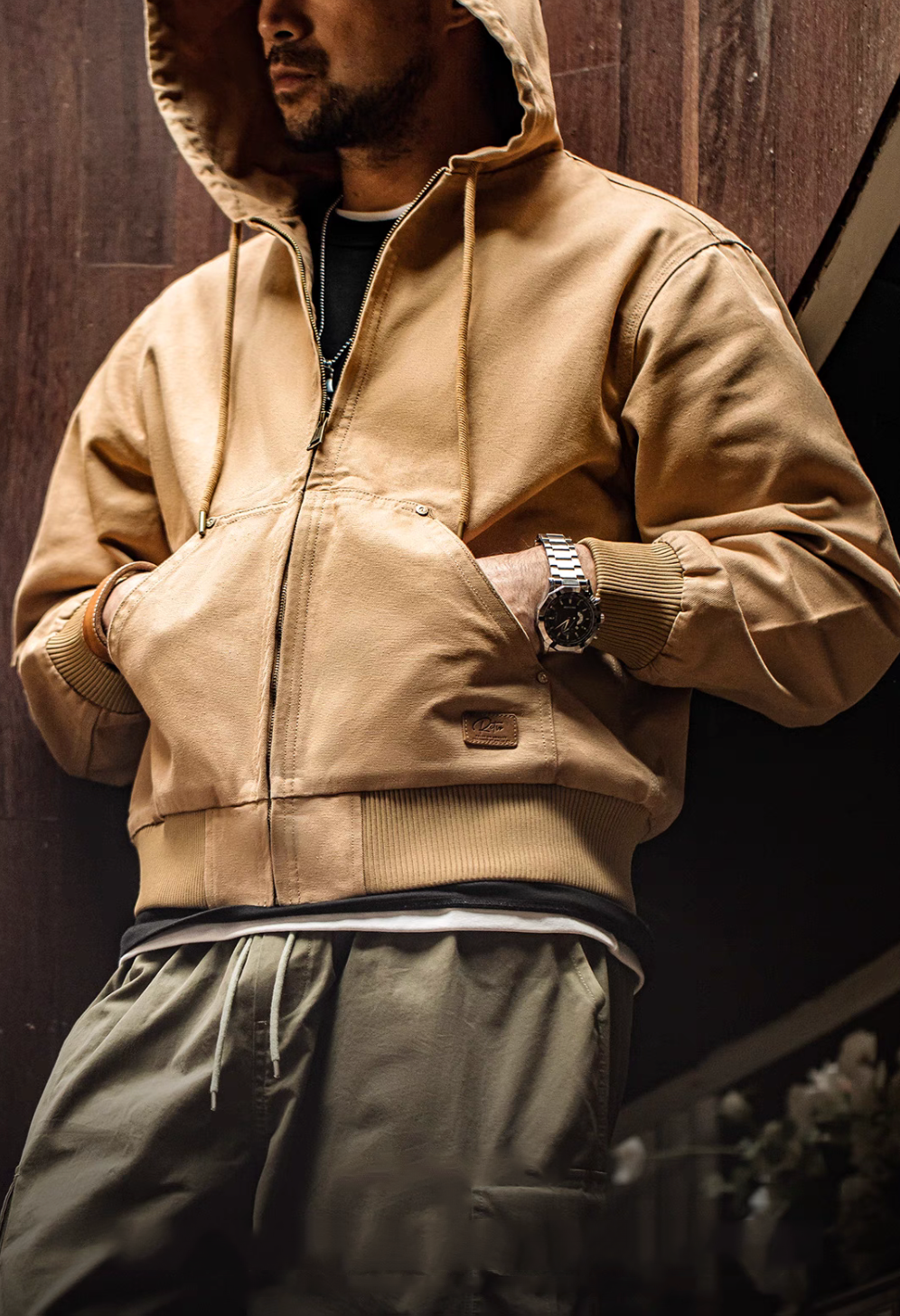 Man wearing Khaki Adventure Ready Hooded Jacket with hands in front pocket highlighting relaxed fit and ribbed hem