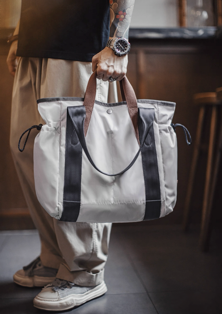 Hand carry view of Ash Gray utility tote bag with brown and black handles