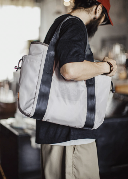 Model wearing Ash Gray outdoor tote bag over shoulder in indoor setting