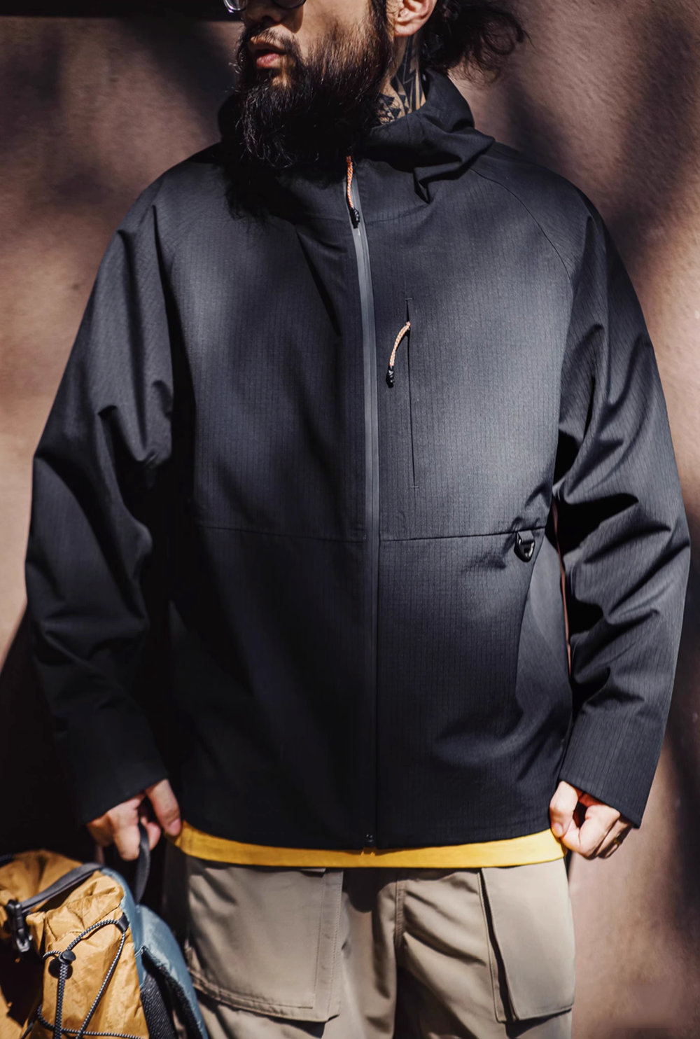 Men wearing black all-weather ripstop shell coat front view with full zip closure and minimalist urban outdoor style
