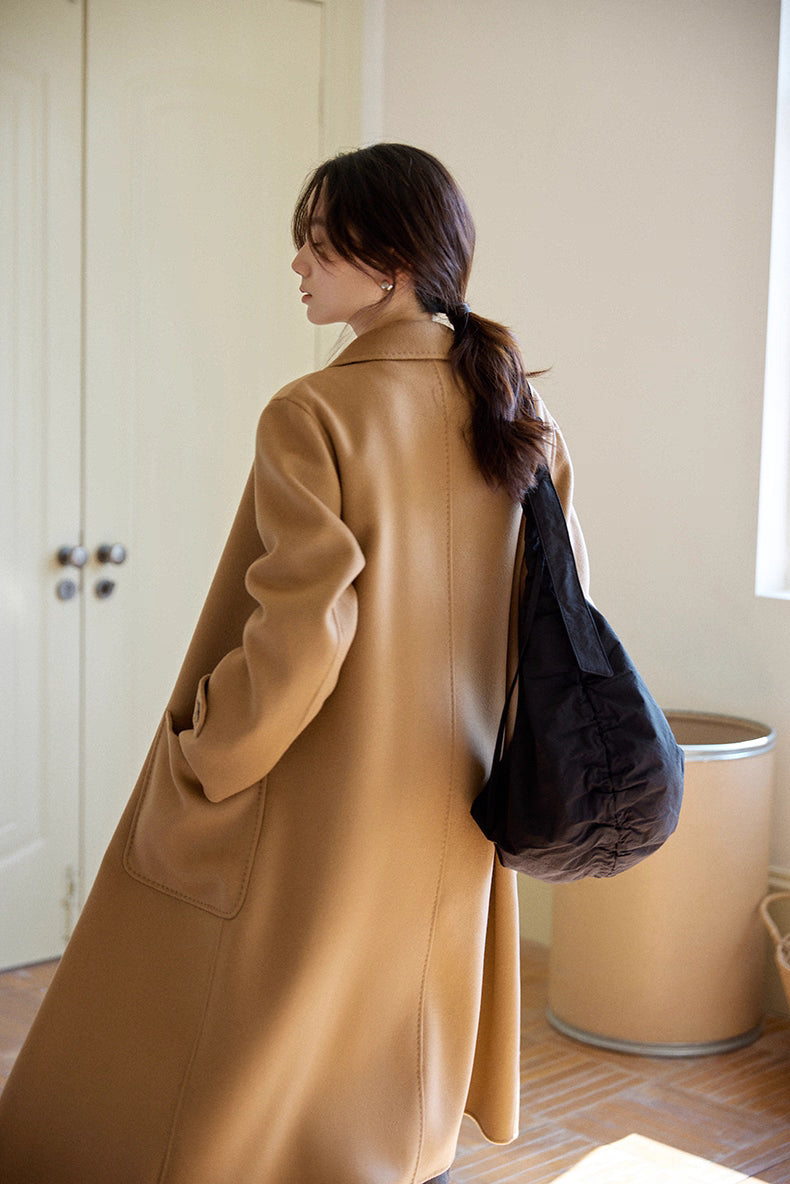 Back view showing relaxed straight silhouette of almond-camel cashmere wool long coat in studio setting