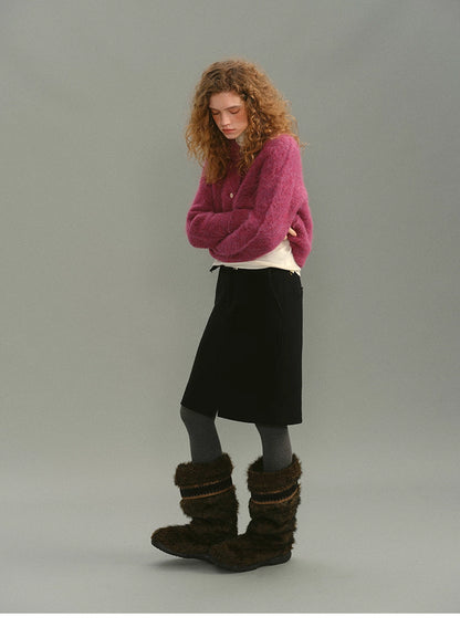 Full-body view of Rose Plum alpaca cardigan styled with black skirt and winter boots